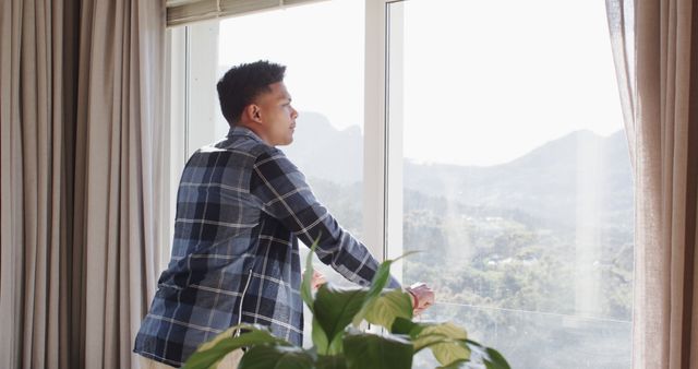 Pensive man looking out window with mountain view - Download Free Stock Images Pikwizard.com