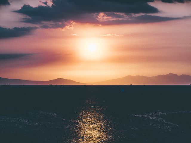 Stunning sunset scene featuring a tranquil sea with sun setting behind silhouetted mountains. Great for promoting travel destinations, nature retreats, meditation content, and ecological awareness campaigns. Ideal for adding a peaceful and serene touch to blogs or websites.
