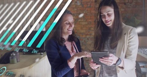 Collaborating businesswomen reviewing tablet and smartphone with sales growth chart overlay