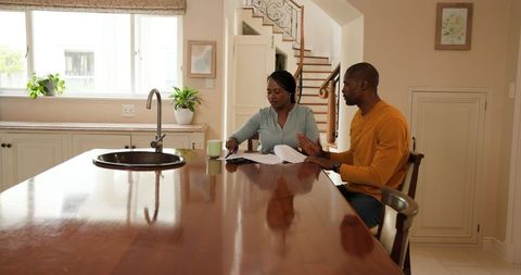 Couple Discussing Papers Over Morning Coffee in Kitchen