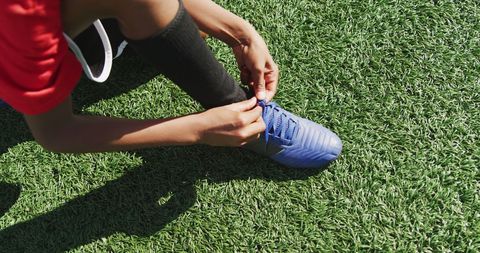 Athlete tying shoelaces on sports field before game