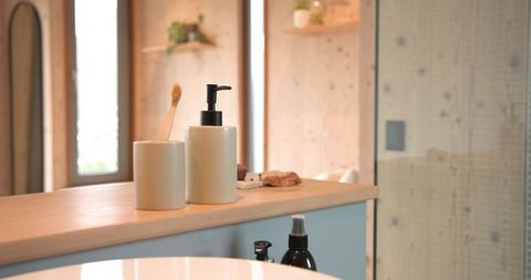 Eco-friendly beige soap dispenser and toothbrush holder in minimalist bathroom