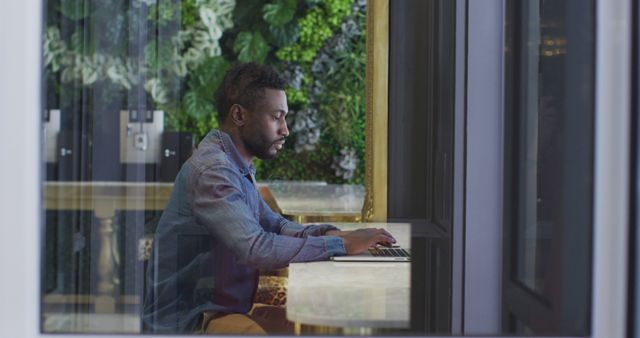 Focused Man Working on Laptop in Modern Office with Green Wall - Download Free Stock Images Pikwizard.com