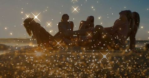 Sunset beach friends relaxing in swimsuits and cover-ups with golden sparkle bokeh