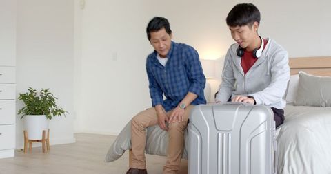 Father and son packing suitcase for travel adventure at home