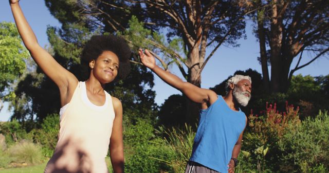 Smiling african american couple exercising outdoors standing stretching in sunny garden. staying at home in isolation during quarantine lockdown.