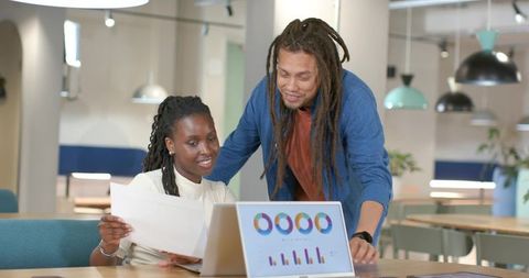 African American coworkers collaborating over data charts on laptop in coworking space