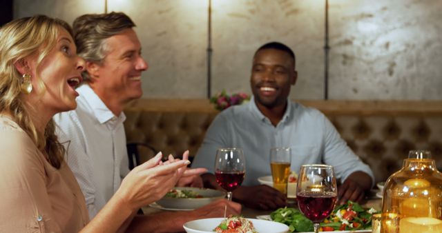 Diverse adults bond over a convivial meal in a cozy restaurant setting. - Download Free Stock Photos Pikwizard.com