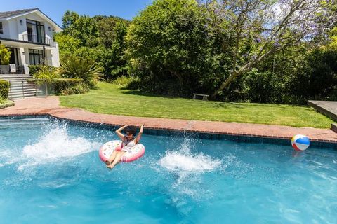 African american woman relaxing on donut float in backyard pool on sunny summer day with beach ball