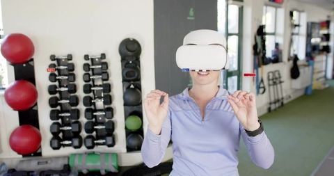 Woman Using VR Headset for Immersive Gym Workout with Dumbbells and Medicine Balls