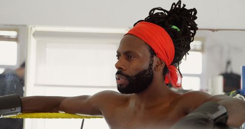 Male Boxer Relaxing in Boxing Ring with Focused Gaze
