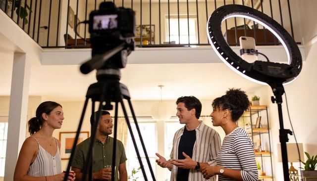 Creators collaborating in loft studio filming content with camera, ring light, smartphone