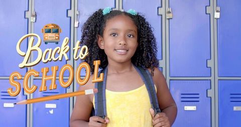 Smiling schoolgirl holding backpack by blue lockers with back to school graphic