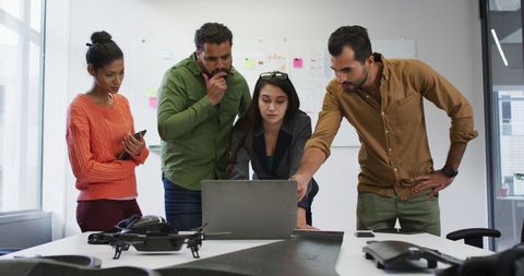 Diverse Team Collaborating Around Laptop in Modern Office Space