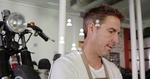 Mechanic Adjusting Motorcycle Front End in Workshop Wearing Apron and T-Shirt
