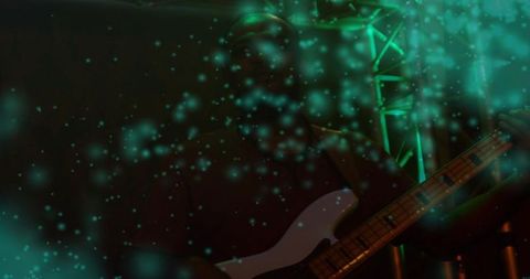 Playing bassist in teal haze on dim stage silhouetted by moody concert lights