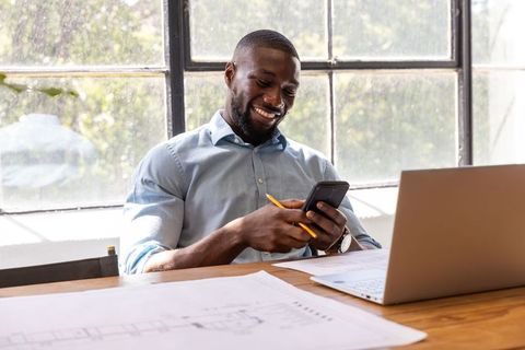 Architect Engineer Using Smartphone in Office Workspace