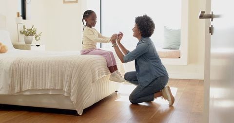 Mother Helps Daughter with Shoelaces in Bright Bedroom