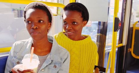 African american twin sisters conversing on bus