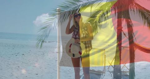 Standing woman on tropical beach holding straw hat and shades with tricolor flag overlay