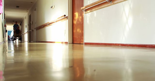 Use this image to depict the emptiness and quietness of a hospital hallway. Perfect for articles or blog posts about hospital environments, healthcare facilities, cleanliness, and safety in medical settings. Could also be applicable for use in flyers, presentations, or advertisements related to medical and healthcare services.