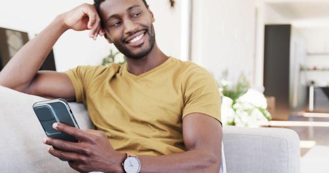 Smiling Man Uses Smartphone While Relaxing on Couch at Home - Download Free Stock Images Pikwizard.com