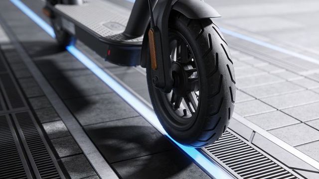 Close-up electric scooter front wheel showing blue led line on urban tiled walkway