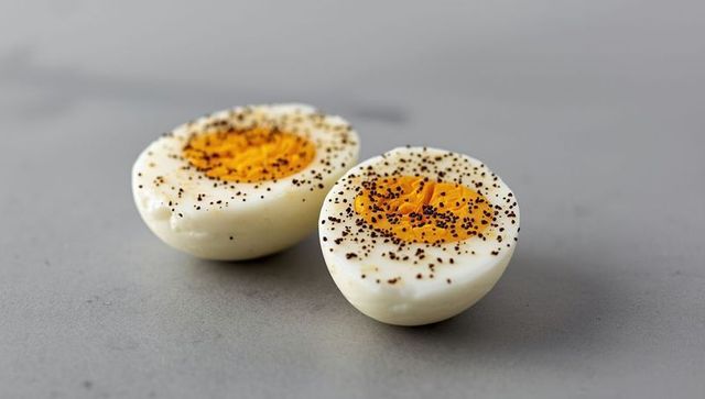 Boiled egg halves with black pepper on minimalist countertop