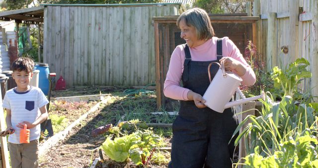 Senior woman watering garden with grandson on sunny day - Download Free Stock Images Pikwizard.com