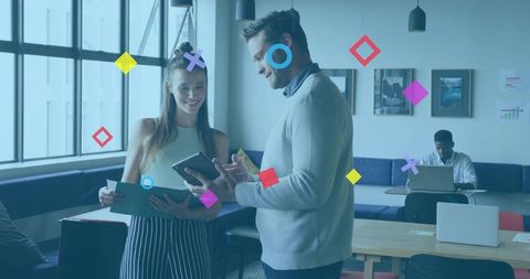 Young professionals collaborating over tablet and folder in modern coworking space