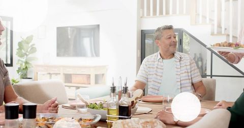Man turning toward server while family shares casual home meal