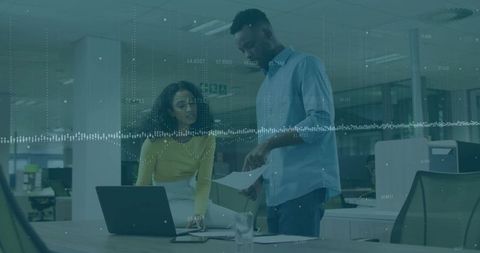 Office colleagues collaborating on business documents with laptop