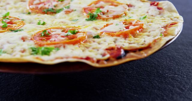 A close-up view of a delicious cheese pizza with tomato toppings on a dark surface, with copy space. Its vibrant colors and melted cheese texture make it an appetizing choice for food enthusiasts.