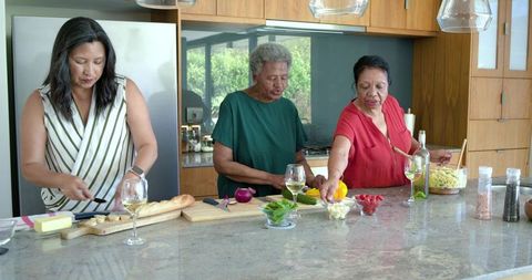 Three generations of african american women cooking together in bright modern kitchen