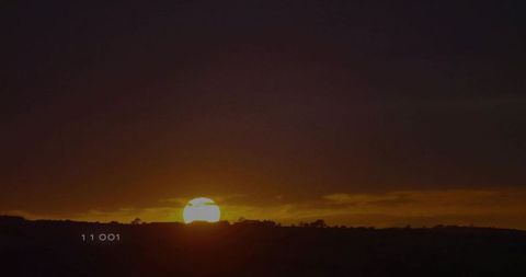 Tranquil Sunset Over Rural Hills with Silhouetted Shrubbery