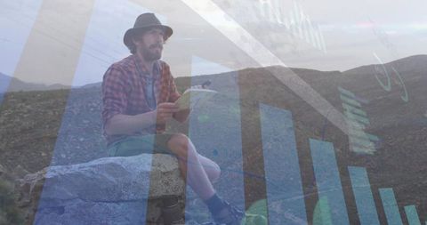 Man flipping notebook while overlaying finance charts and down arrow over rocky ridge