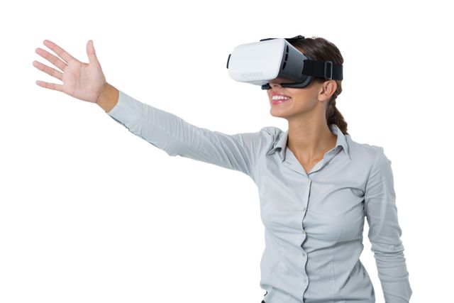 Businesswoman wearing VR headset, smiling and interacting with virtual environment. Ideal for illustrating concepts of modern technology, innovation in business, and the use of virtual reality in professional settings. Suitable for articles, presentations, and marketing materials related to tech advancements and workplace innovation.