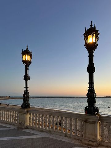 Elegant street lamps along a coastal promenade at sunset