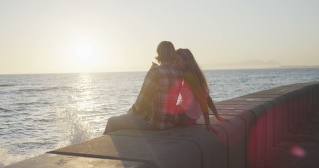 Romantic caucasian couple sitting and talking on beach at sunset. Vacations, romance, love nature and relaxation, unalterned.