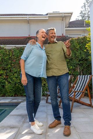 Senior Couple Embracing on Patio by Swimming Pool in Casual Attire
