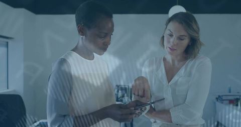 Female Professionals Collaborating on Touchscreen Device in Modern Office