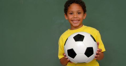 Smiling Schoolboy Holding Soccer Ball Against Chalkboard Background - Download Free Stock Images Pikwizard.com