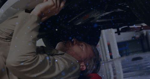 Mechanic maintaining underneath vehicle in auto workshop