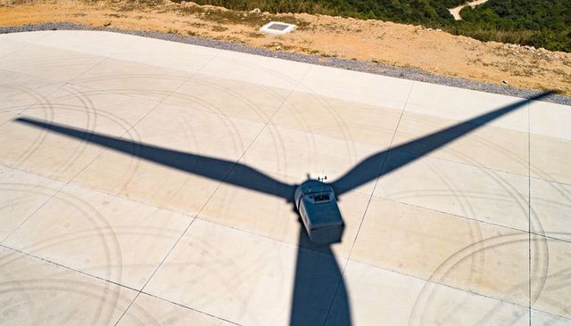 Casting wind turbine shadow over concrete pad with maintenance vehicle and tire marks
