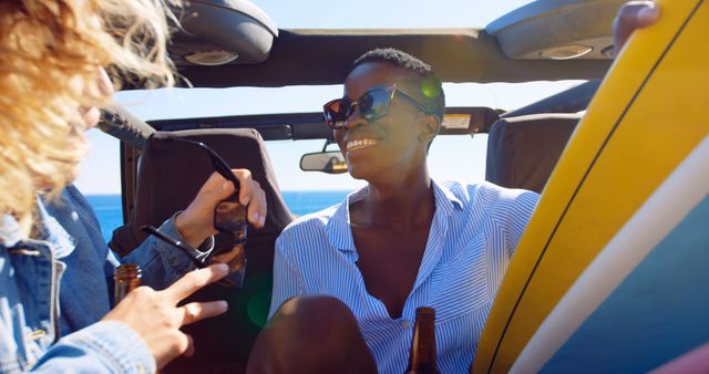 Young friends conversing happily in a convertible near the ocean. Perfect for content about road trips, summer getaways, friendship, and carefree lifestyle. Ideal for travel blogs, tourism promotions, and products targeting young travelers.