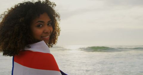 Smiling Woman Wrapped in American Flag on Beach