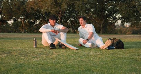Cricket Teammates Sitting on Field Chatting and Relaxing at Golden Hour