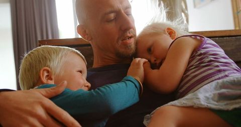 Father Embracing Young Children on Cozy Sofa at Home