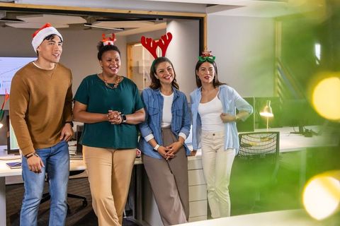 Holiday office team wearing santa hats and reindeer antlers in open-plan workspace