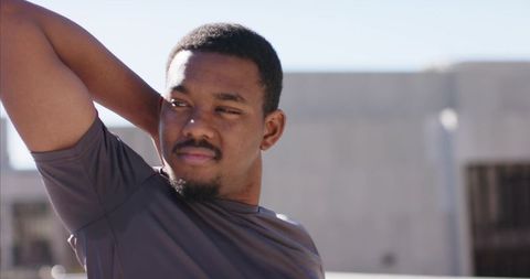 African American man stretching on rooftop in sunlight urban fitness portrait